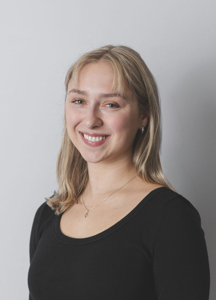 Smiling Be Fitness instructor wearing black top against neutral background