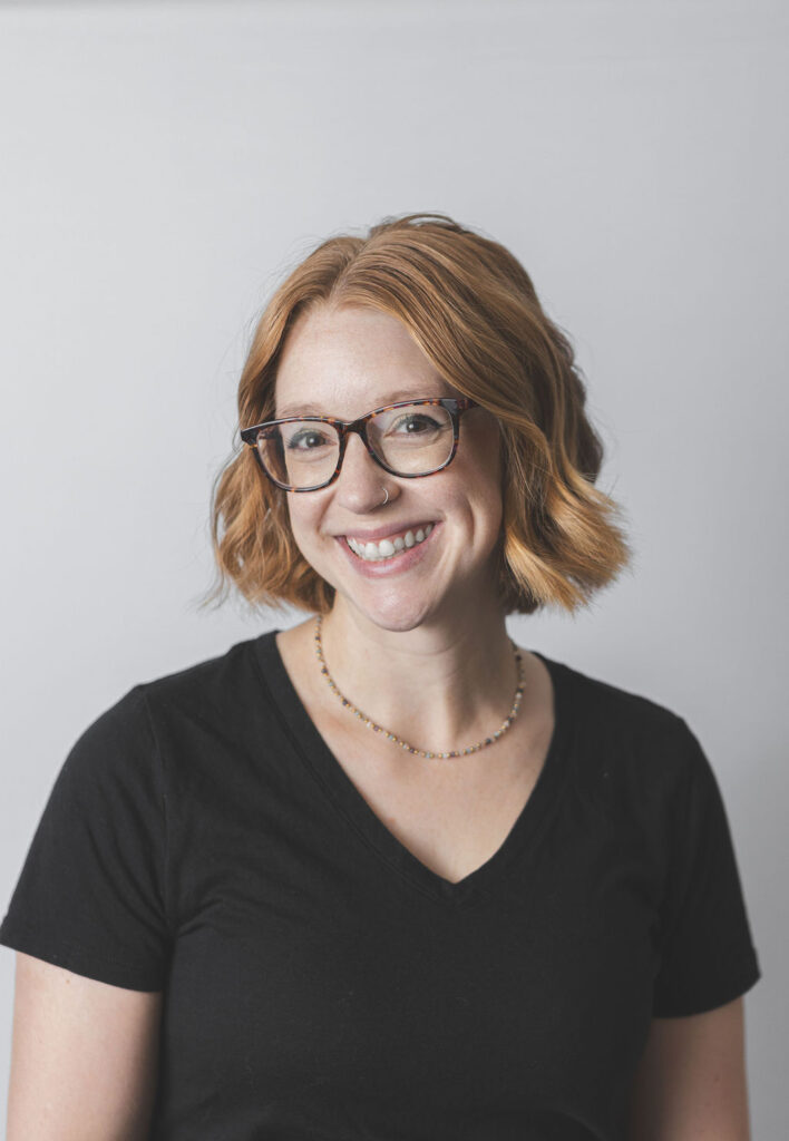 Smiling Be Fitness instructor wearing black top against neutral background