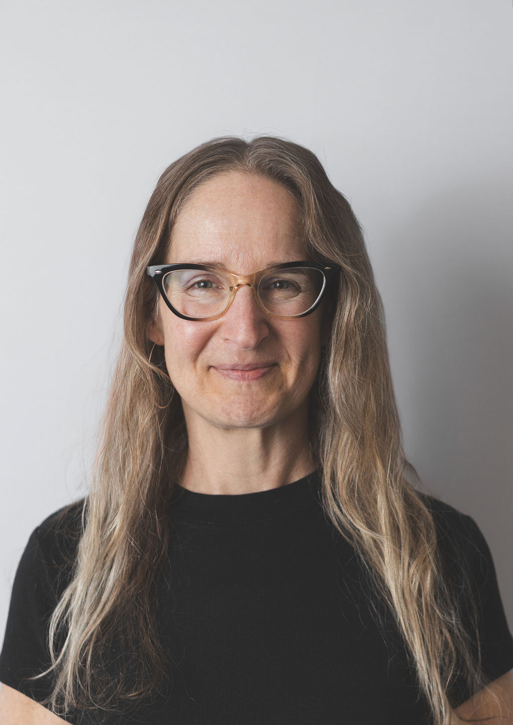 Smiling Be Fitness instructor wearing black top against neutral background