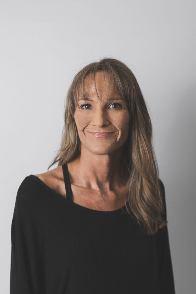 Smiling Be Fitness instructor wearing black top against neutral background