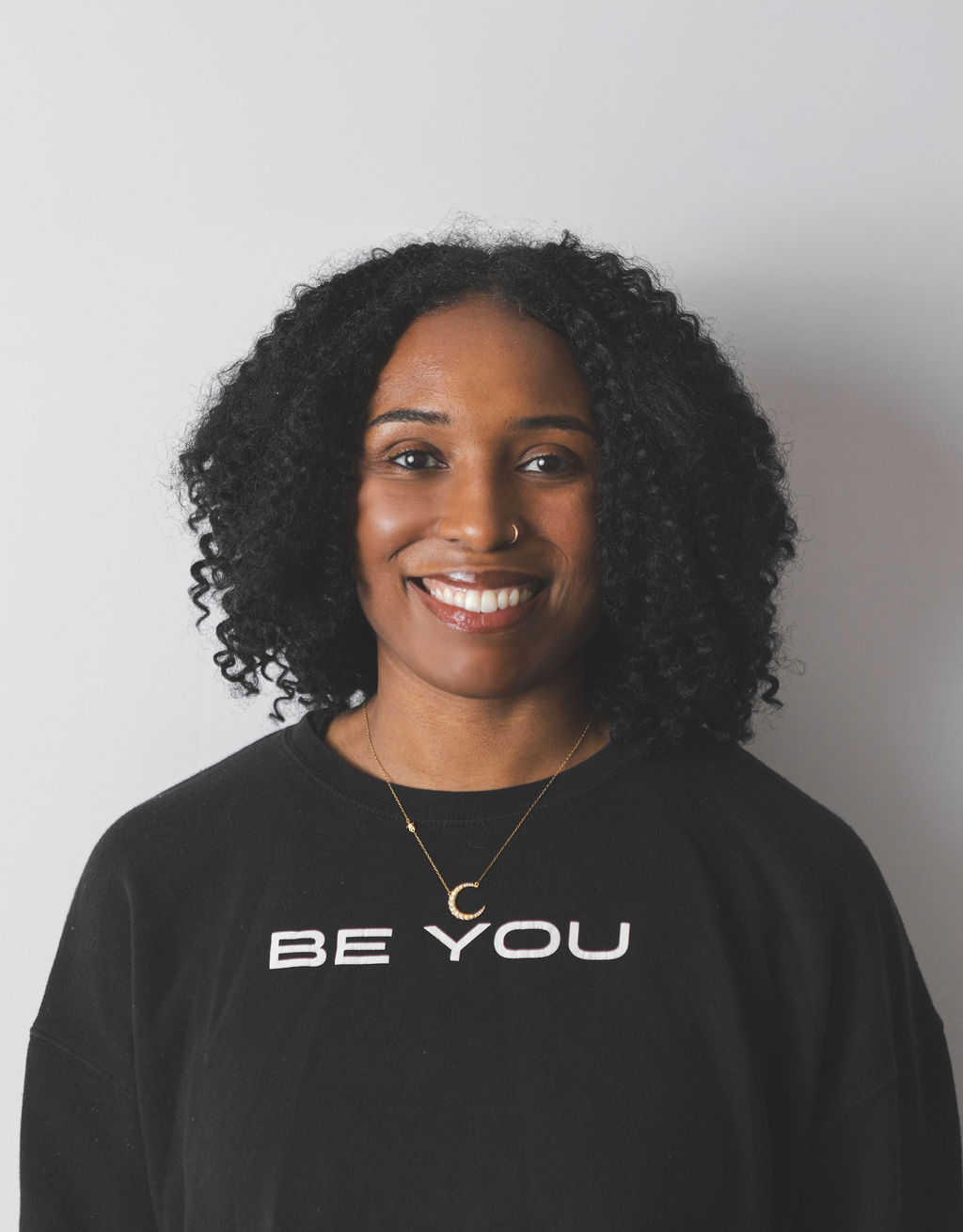 Smiling Be Fitness instructor wearing black top against neutral background