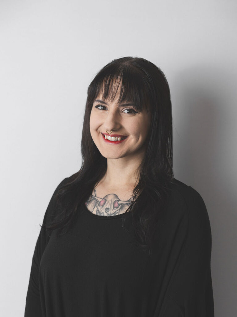 Smiling Be Fitness instructor wearing black top against neutral background