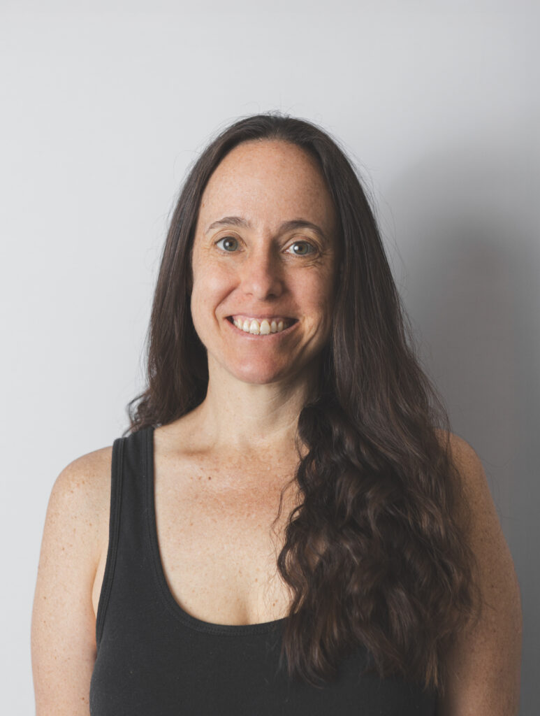 Smiling Be Fitness instructor wearing black top against neutral background