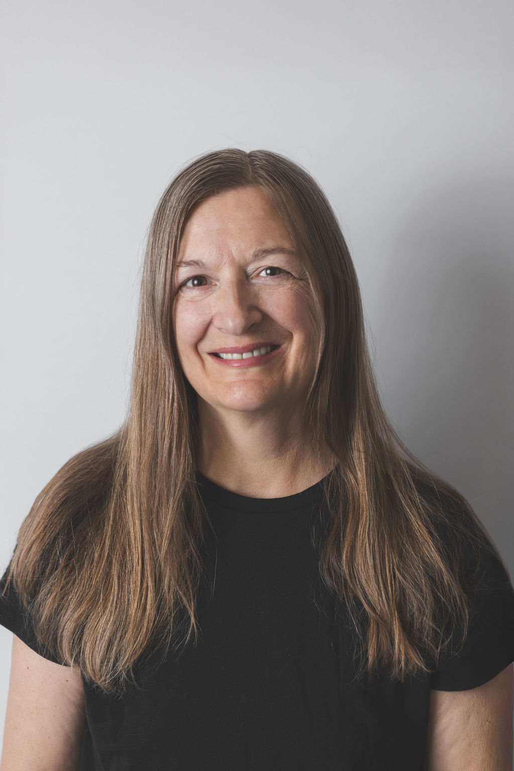 Smiling Be Fitness instructor wearing black top against neutral background