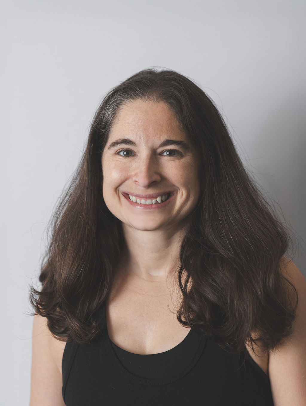 Smiling Be Fitness instructor wearing black top against neutral background
