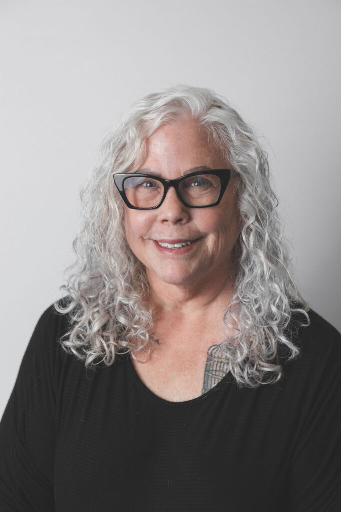 Smiling Be Fitness instructor wearing black top against neutral background