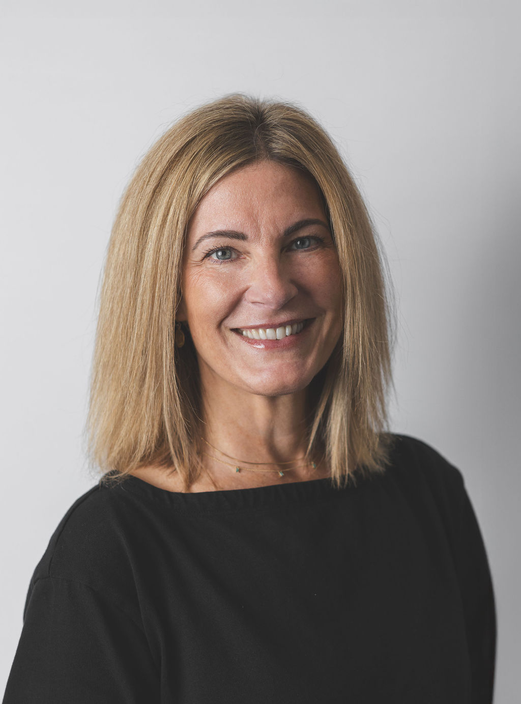Smiling Be Fitness instructor wearing black top against neutral background