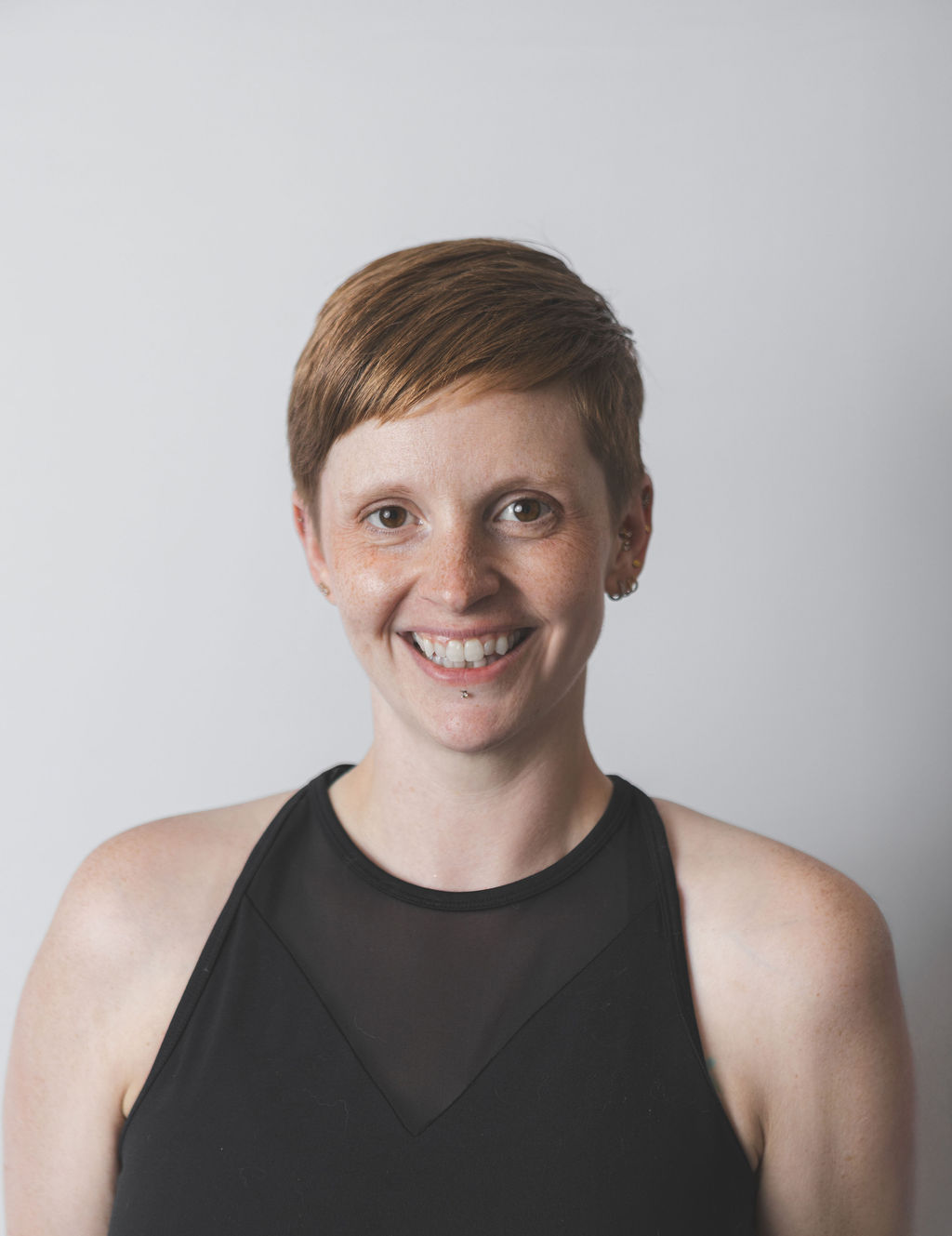 Smiling Be Fitness instructor wearing black top against neutral background
