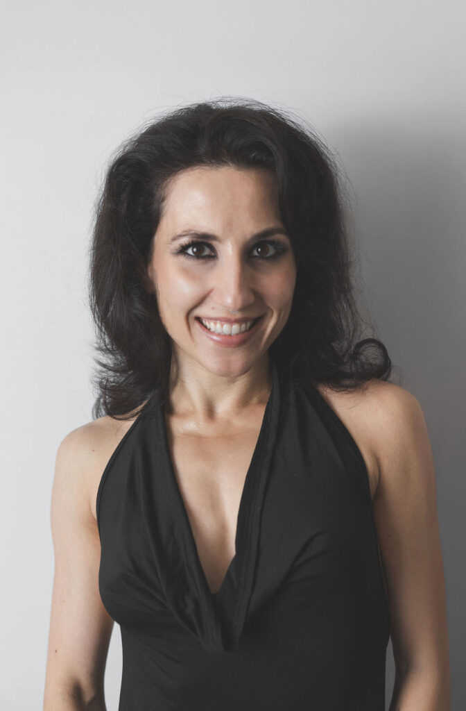 Smiling Be Fitness instructor wearing black top against neutral background