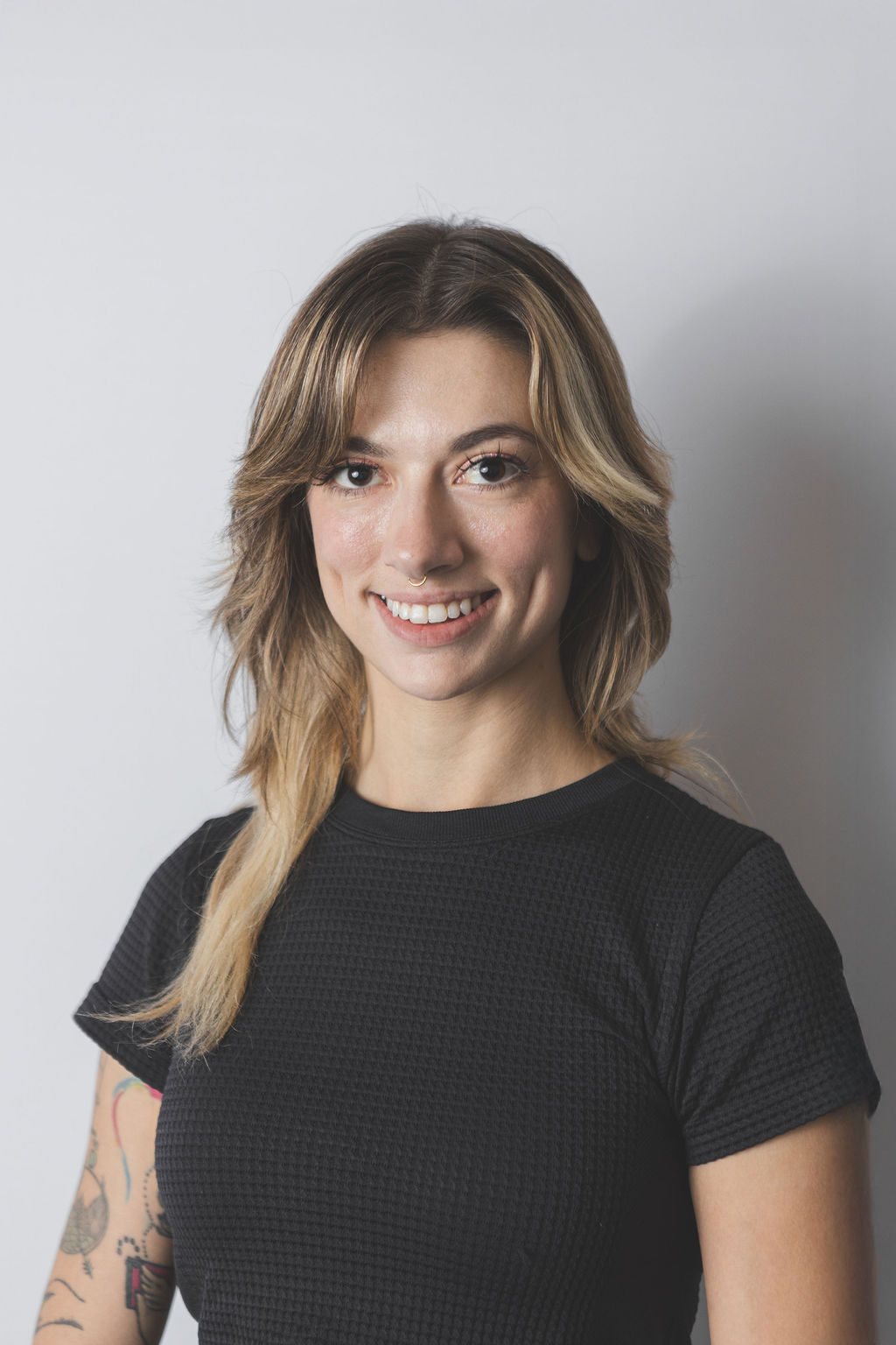 Smiling Be Fitness instructor wearing black top against neutral background