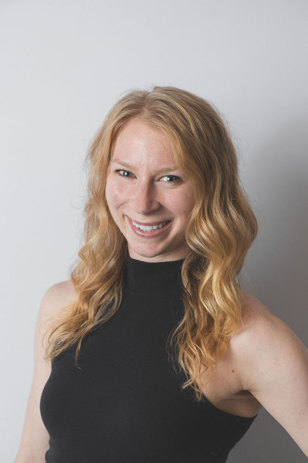 Smiling Be Fitness instructor wearing black top against neutral background