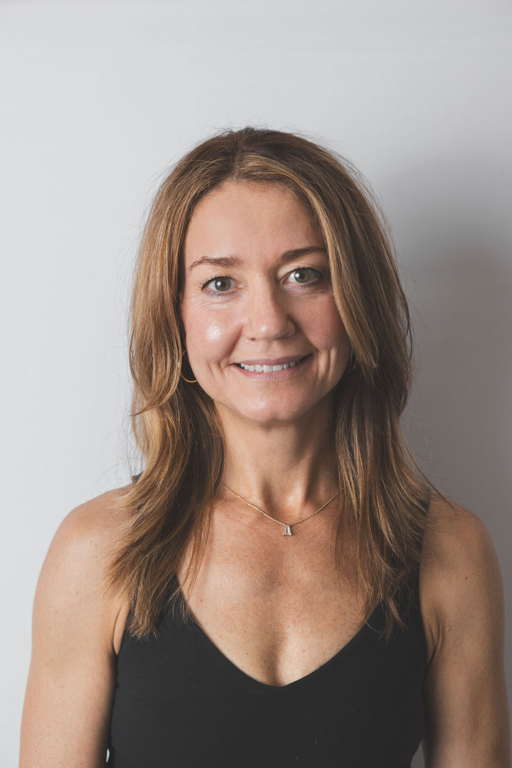 Smiling Be Fitness instructor wearing black top against neutral background