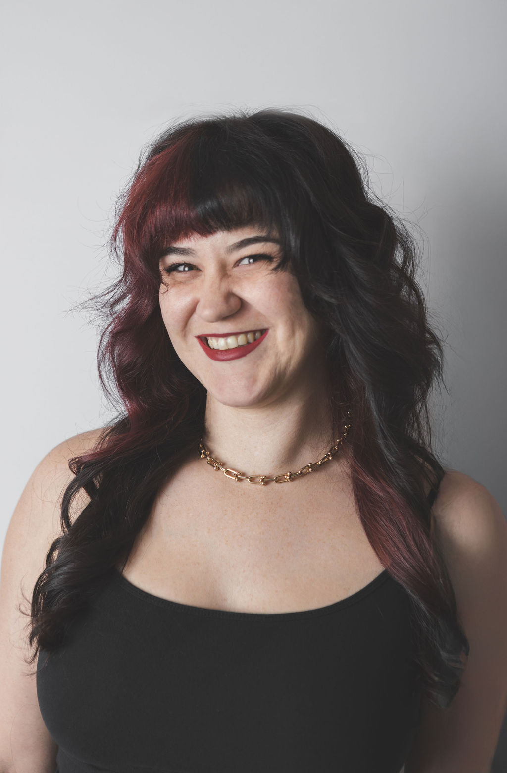 Smiling Be Fitness instructor wearing black top against neutral background