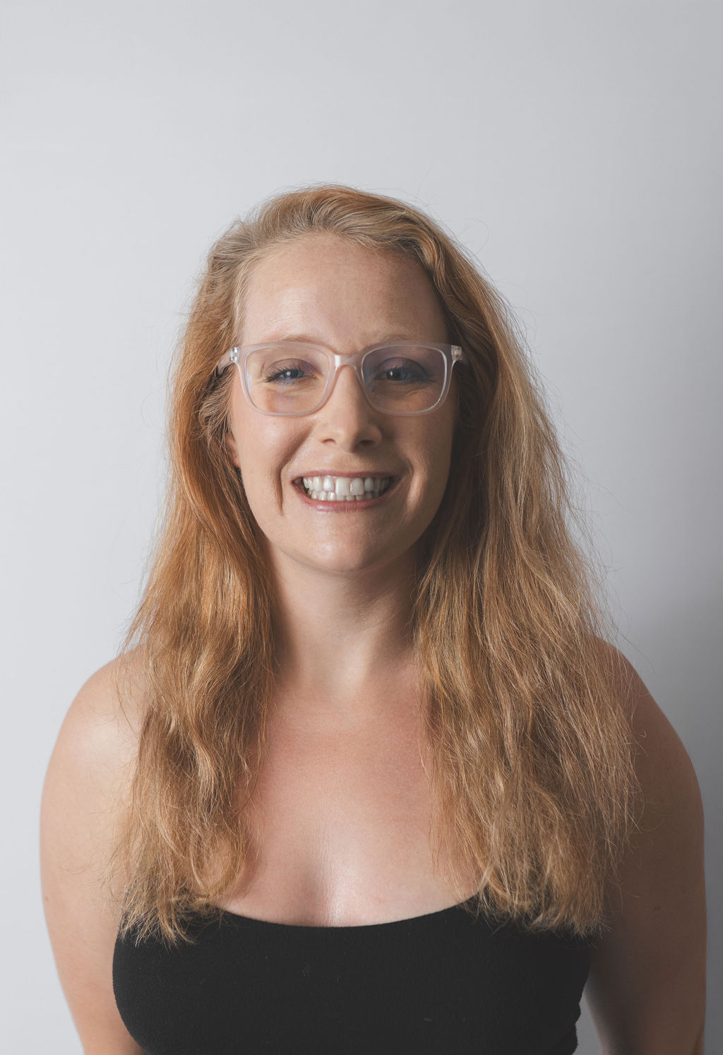 Smiling Be Fitness instructor wearing black top against neutral background