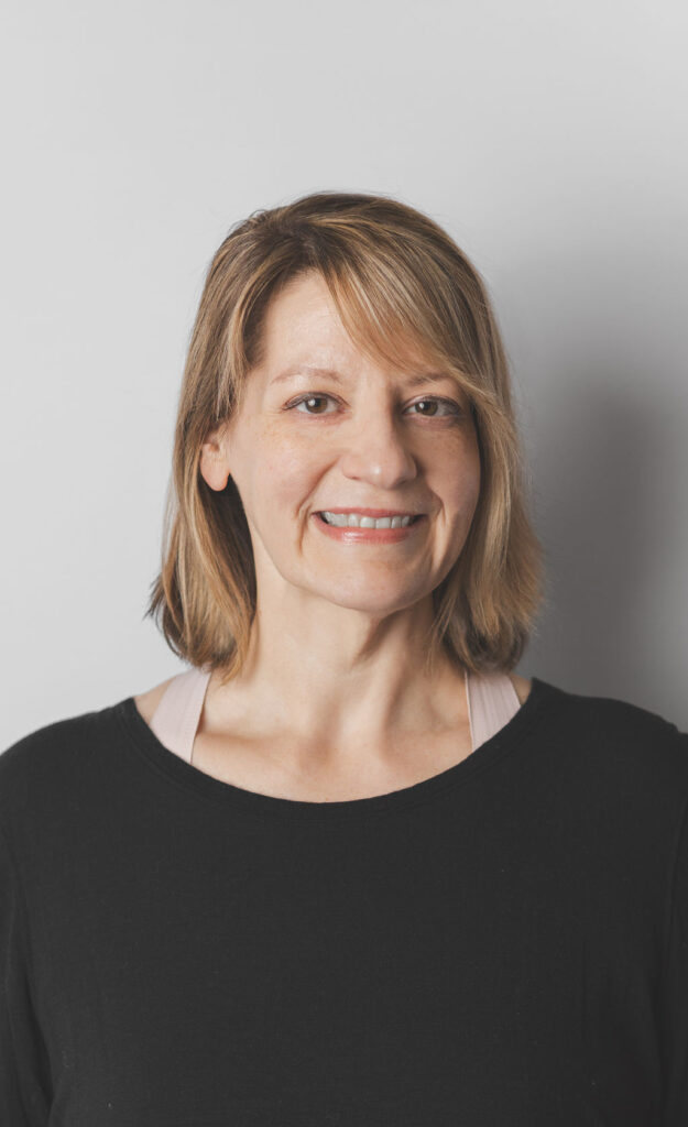 Smiling Be Fitness instructor wearing black top against neutral background