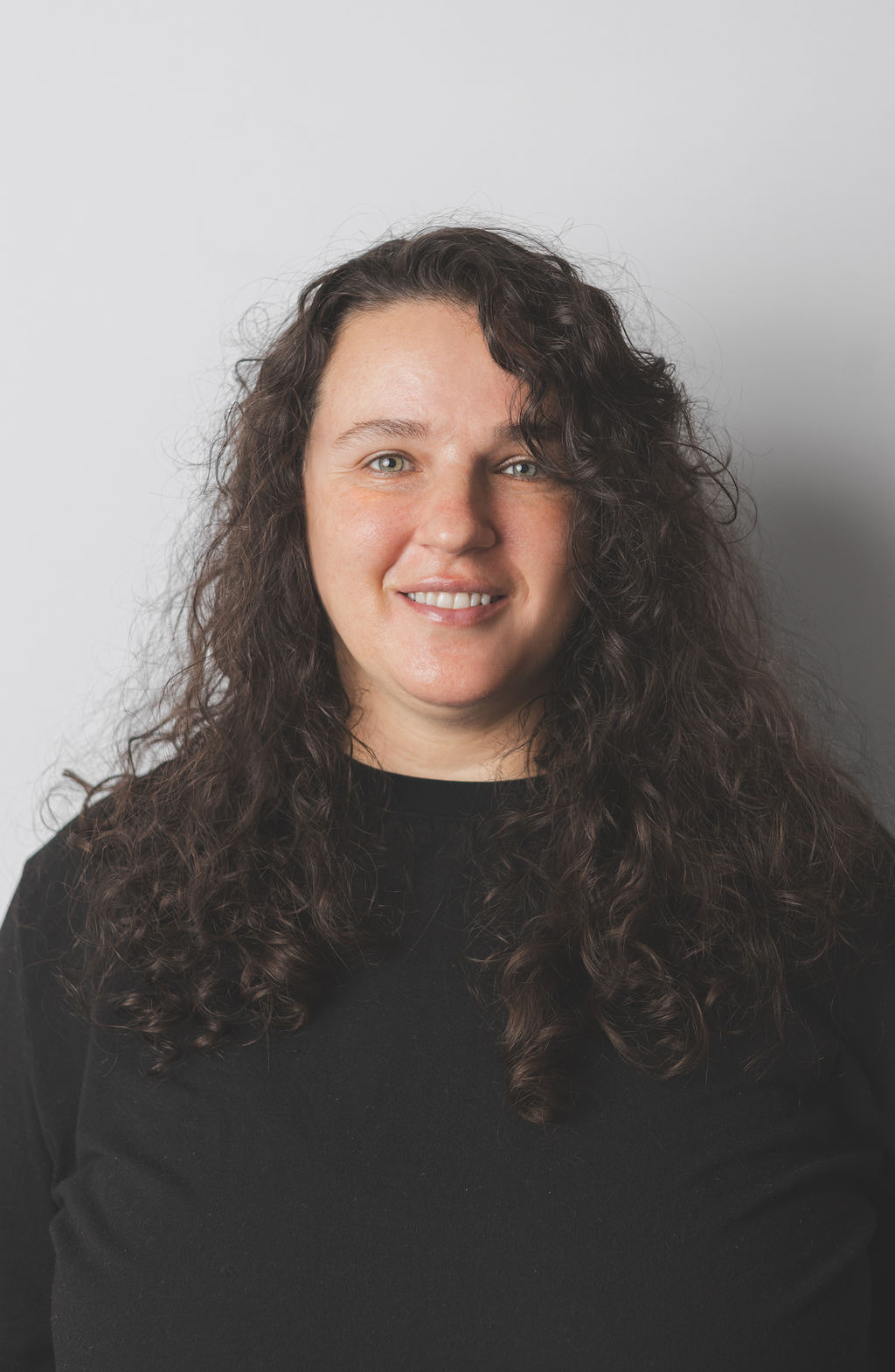 Smiling Be Fitness instructor wearing black top against neutral background