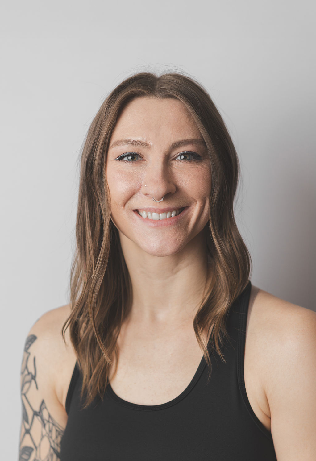 Smiling Be Fitness instructor wearing black top against neutral background