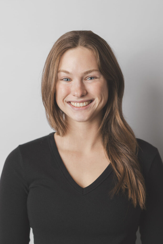 Smiling Be Fitness instructor wearing black top against neutral background