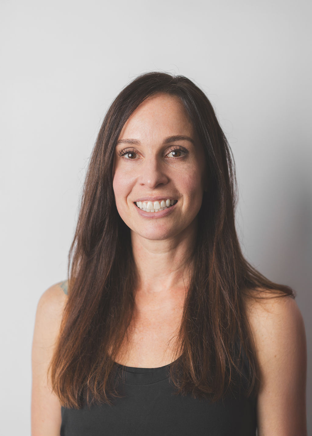 Smiling Be Fitness instructor wearing black top against neutral background