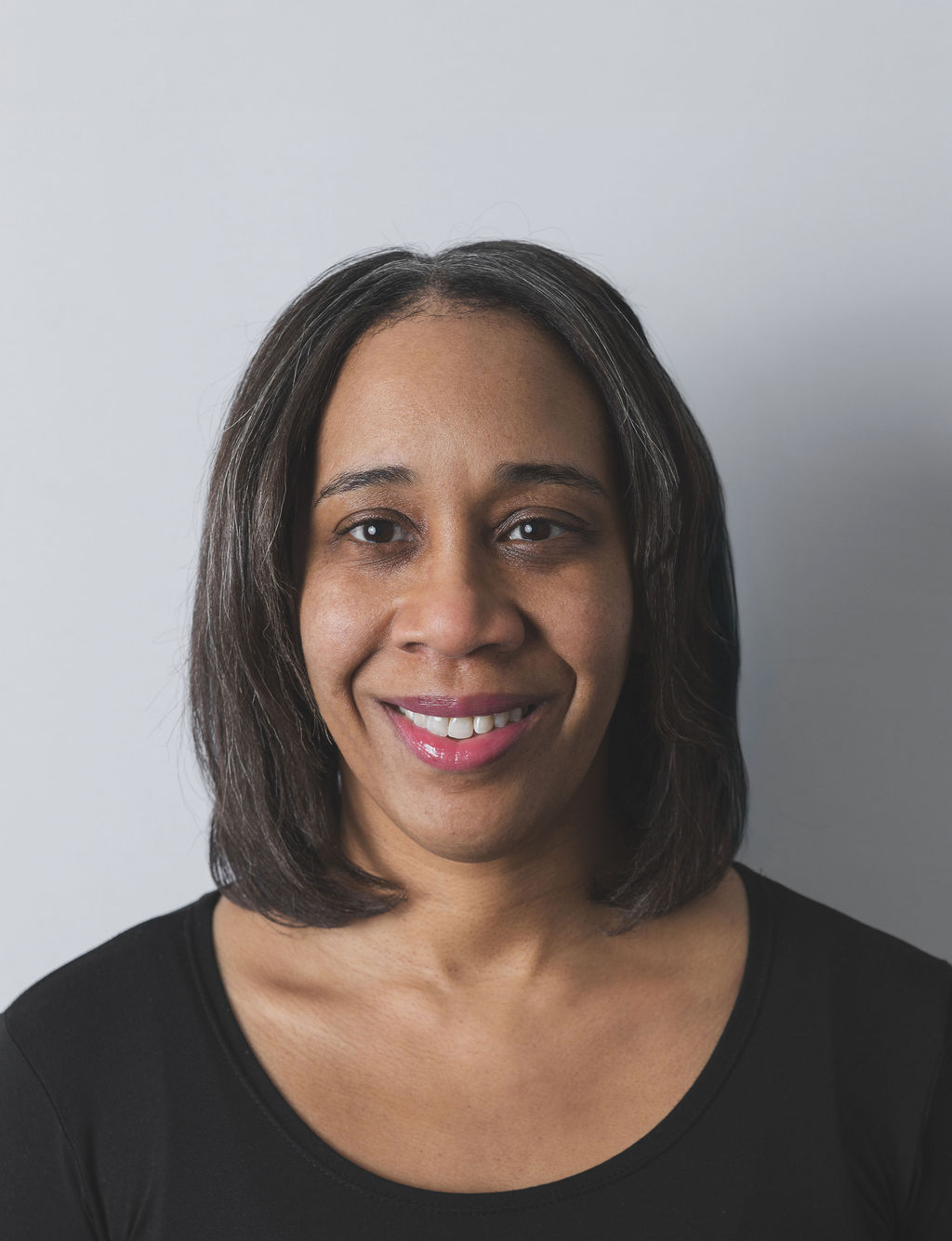 Smiling Be Fitness instructor wearing black top against neutral background