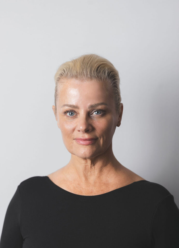 Smiling Be Fitness instructor wearing black top against neutral background