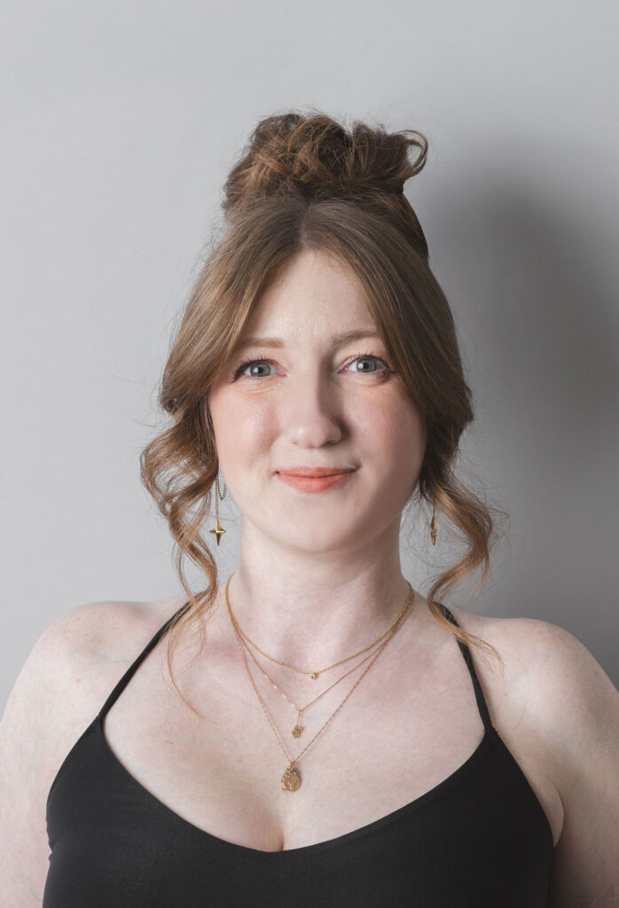 Smiling Be Fitness instructor wearing black top against neutral background