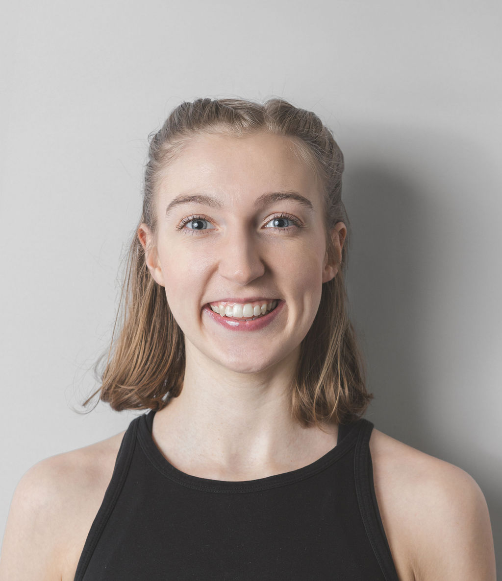 Smiling Be Fitness instructor wearing black top against neutral background