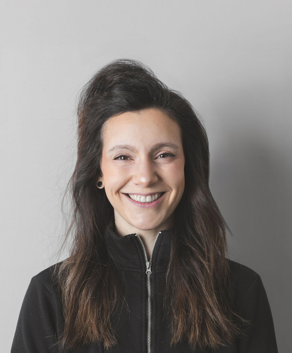 Smiling Be Fitness instructor wearing black top against neutral background