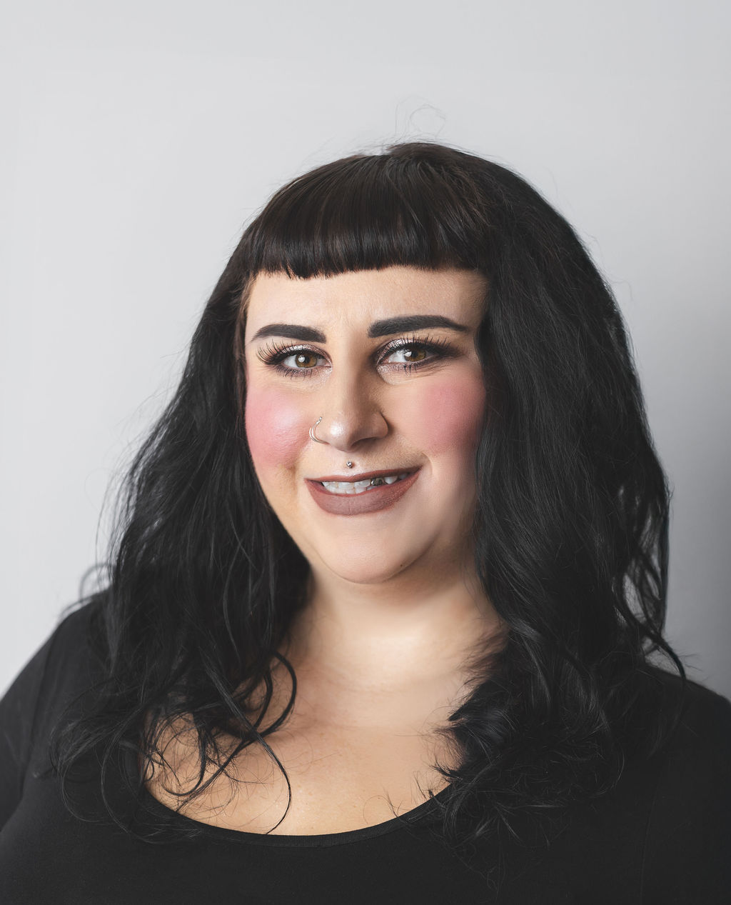 Smiling Be Fitness instructor wearing black top against neutral background