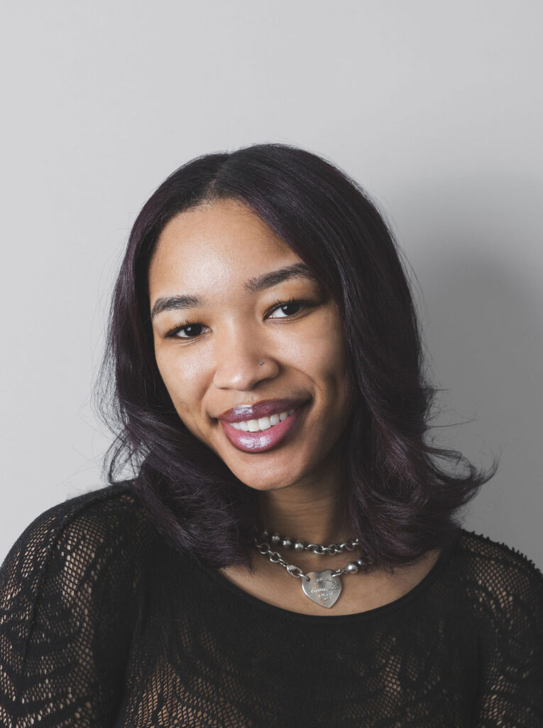 Smiling Be Fitness instructor wearing black top against neutral background