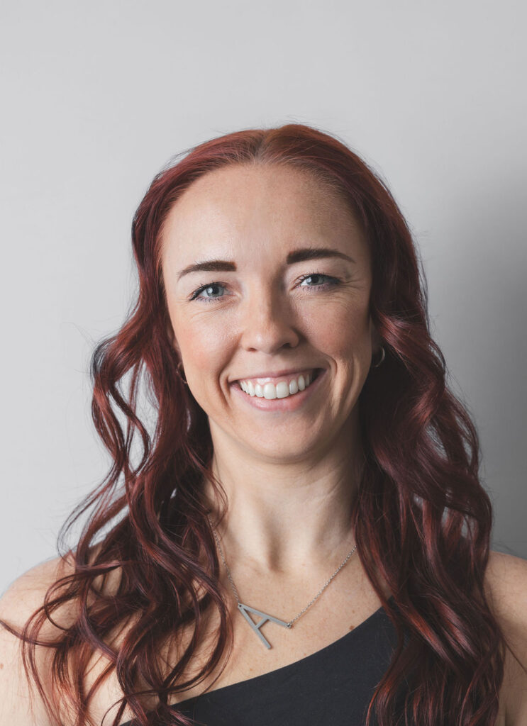 Smiling Be Fitness instructor wearing black top against neutral background