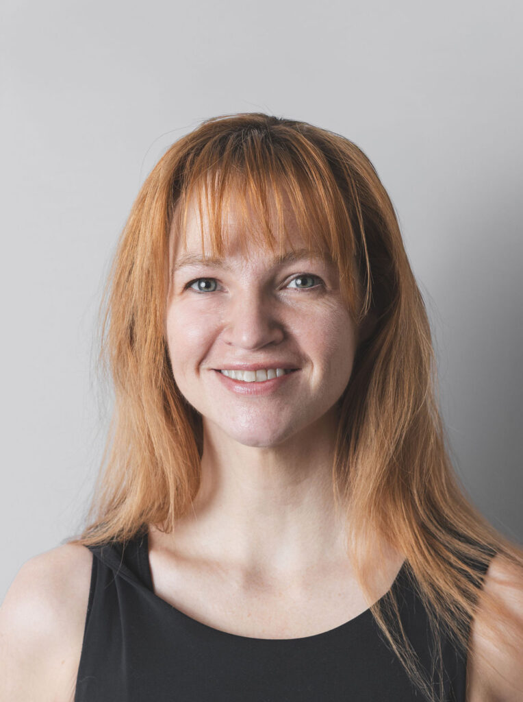 Smiling Be Fitness instructor wearing black top against neutral background